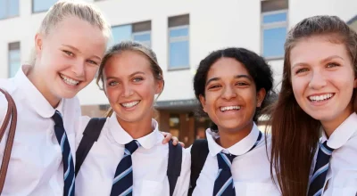 Porträt lächelnder Schülerinnen in Schuluniform vor dem Collegegebäude