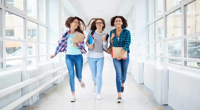 Raparigas felizes a correr pelo corredor depois das aulas