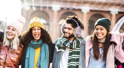 Happy students group walking at european city on sunny day - Next gen life style concept with multiracial young people wearing winter fashion clothes having fun together outdoors - Backlight filter