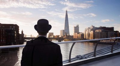 Homme portant un chapeau melon sur le Millennium Bridge qui enjambe la Tamise à Londres