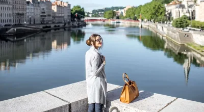 Piękna i elegancka kobieta ciesząca się porannym widokiem miasta, stojąca w pobliżu rzeki na starym mieście w Lyonie we Francji