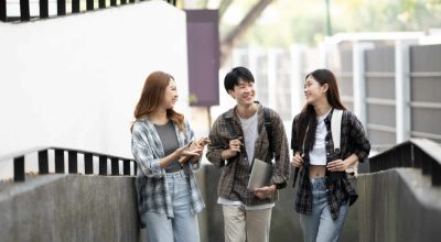 Cheerful college students having the conversation before the classroom starts. Friendship, Education concept.