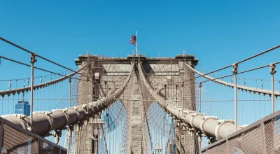 Most Brookliński z amerykańską flagą na tle czystego, błękitnego nieba, Nowy Jork, USA
