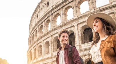 Young couple at the Colosseum, Rome - Happy tourists visiting Italian famous landmarks