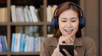 Asian tutor of language start online lesson with trainee wave hand smiling looks at pc screen. woman in headphones communicating distantly, e-learning process, application usage concept.