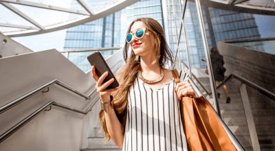 Mulher de negócios jovem e bonita, de pé com o telefone ao ar livre, nas escadas perto de escritórios modernos na cidade de Bruxelas