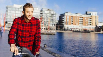 Irlanda, Dublin, jovem no cais da cidade com uma bicicleta urbana