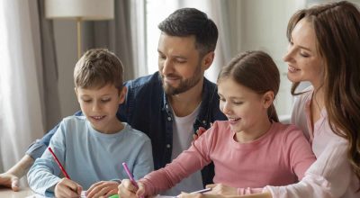 Family of four parents and kids engaging in studying and learning together in a warm home environment