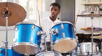 Male Teenage Pupil Playing Drums In Music Lesson