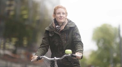 Student cycling away from University Library, Freiburg, Germany