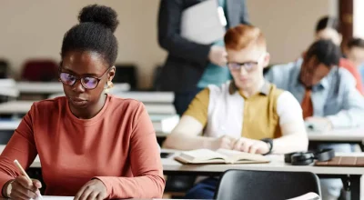 Diverse group of students taking notes in row during lecture in college or university, copy space