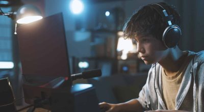 Cool teenager wearing headphones and playing online video games, gaming and entertainment concept