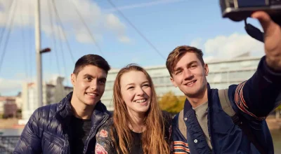 Trzech przyjaciół siedzi na zewnątrz i robi sobie selfie aparatem, Bristol, Wielka Brytania
