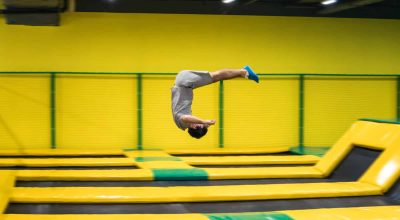 O saltador de trampolim executa exercícios acrobáticos complexos e dá cambalhotas no trampolim.