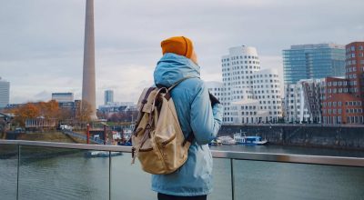 viaggio autunnale o invernale a Dusseldorf, Germania. giovane turista o studente asiatico in giacca blu e cappello giallo (simbolo dell'Ucraina) cammina tra le attrazioni della città europea. bella vista nella Media Bay