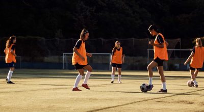 Jogadoras de futebol a praticar com uma bola num treino desportivo. Espaço de cópia.